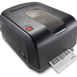 A Honeywell barcode label printer in matte black, shown with a white barcode label partially ejected from the front.