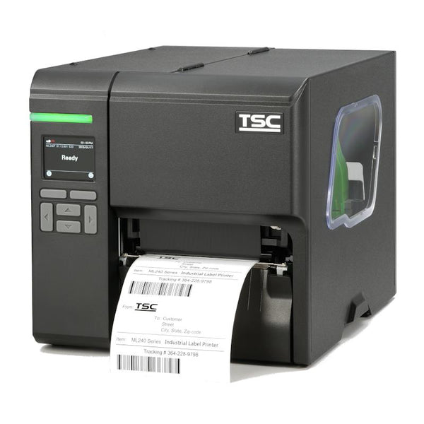 A TSC industrial label printer in matte black, shown from a three-quarter angle with a white label sheet partially ejected from the front slot. The printer features a small display screen on the left, a green status light, and a clear side window.