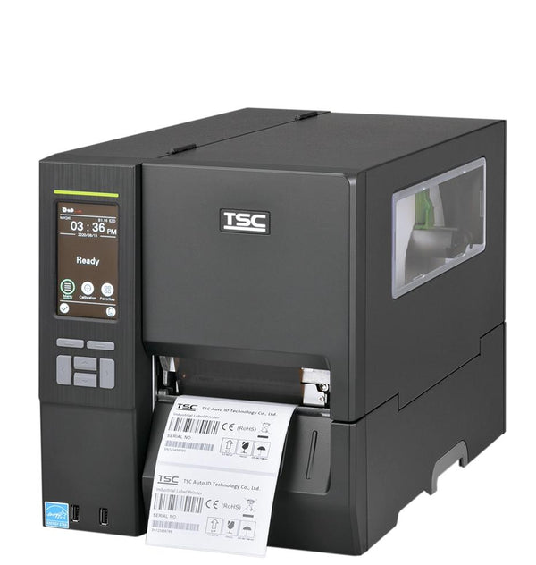 A TSC industrial barcode label printer with a dark gray and silver metallic body, showing a digital control screen on the front left and a white label sheet being printed and ejected from the front right.