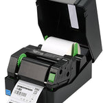 A black thermal label printer with its lid open, showing a white label roll inside and a printed label sheet coming out. The printer has small green accents and is photographed on a plain white background.