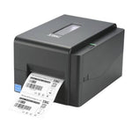A black TSC thermal label printer with a white label sheet emerging from the front, shown on a plain white background.