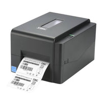 A black TSC thermal label printer with a white label sheet emerging from the front, shown on a plain white background.
