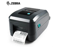 A Zebra QR-GT800 barcode scanner with a black and gray body, featuring a digital display screen and control buttons on top, with a white paper label partially ejected from the front, set against a plain white background.