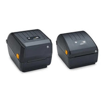 Two black Zebra thermal label printers shown side by side on a plain white background, with one printer displaying a ZEBRA logo on the top panel.